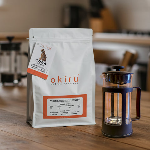 okiru coffee roasters TORA package on a wooden table with a French press in the background