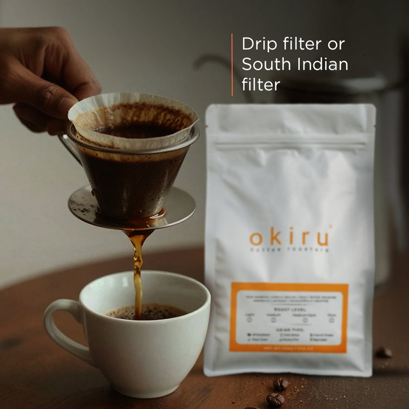 Person pouring coffee from a filter into a cup with okiru coffee package in the background.