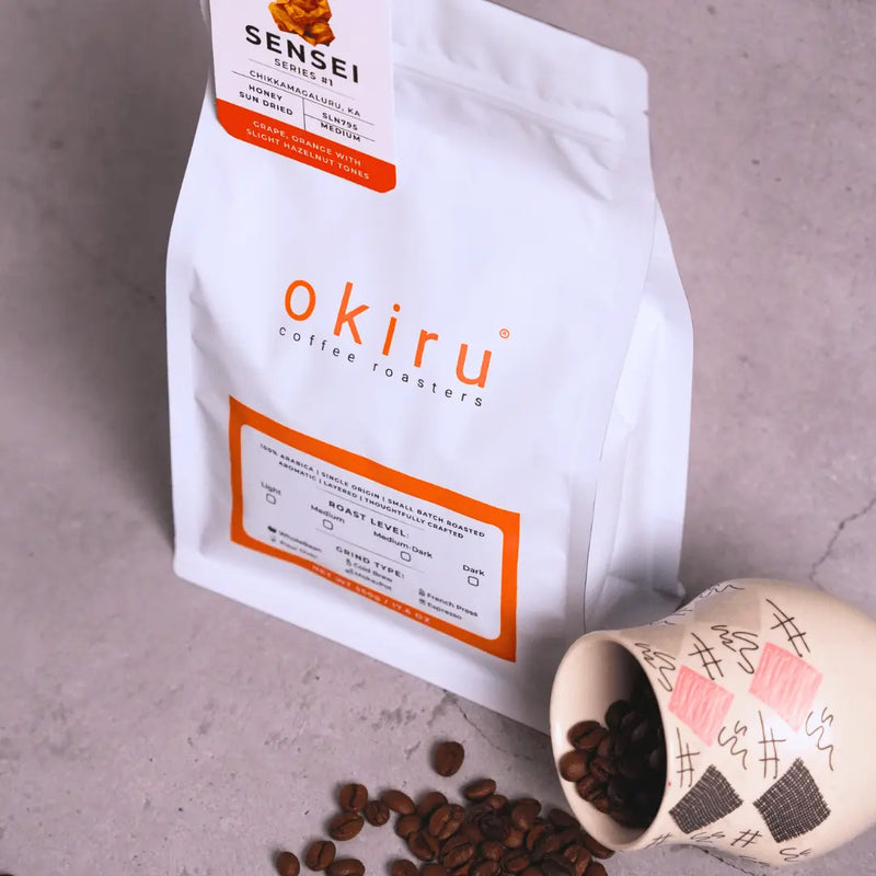 okiru coffee roasters packaging with coffee beans and a cup on a gray surface